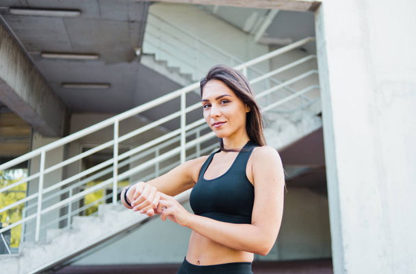 Attraente donna sportiva in abbigliamento sportivo utilizzare smart watch all'aperto in ambiente urbano
 - Foto, immagini