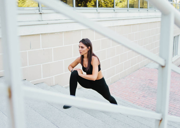 jovem ajuste mulher fazendo alongamento pernas exercício em escadas ao ar livre em ambiente urbano - Foto, Imagem