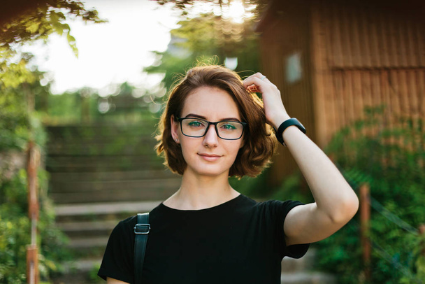 Porträt einer jungen Frau mit Kurzhaarschnitt und Brille im Freien - Foto, Bild