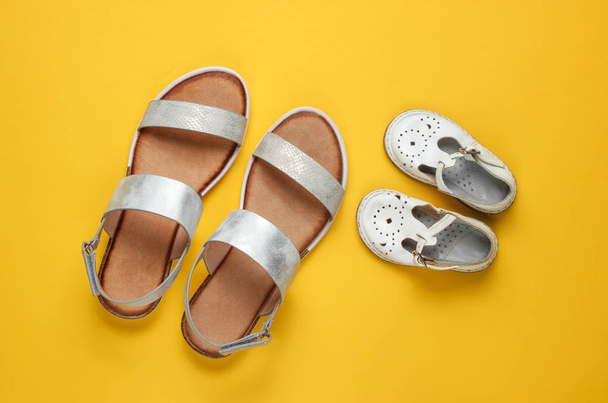 Sandalias de moda para niños y adultos sobre fondo amarillo. Vista superior
 - Foto, imagen