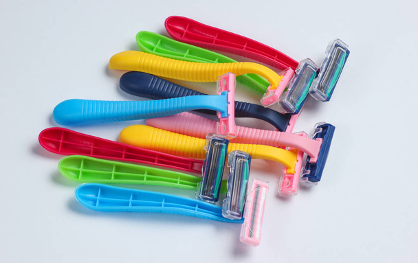 Muchas máquinas de afeitar de plástico de color sobre fondo blanco de cerca
 - Foto, imagen