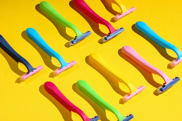 Belleza y moda concepto de arte pop. Muchas maquinillas de afeitar de plástico de color sobre un fondo amarillo. Minimalismo
 - Foto, imagen