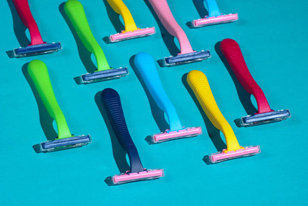 Belleza y moda concepto de arte pop. Muchas maquinillas de afeitar de plástico de color sobre fondo azul. Minimalismo
 - Foto, imagen