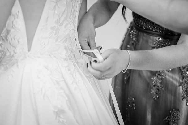 Bridesmaids assist bride to wear wedding dress - Photo, Image