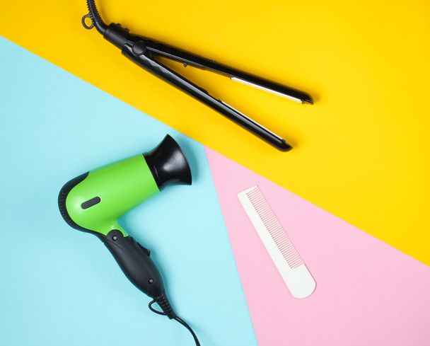 Minimalistic beauty and fashion still life. Hair dryer, comb and hair straightener on colored background. Top view, flat lay - Foto, immagini