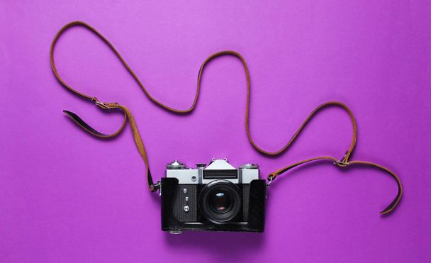 Mor arka planda kayışı olan deri kapaklı klasik retro film kamerası. Üst görünüm - Fotoğraf, Görsel