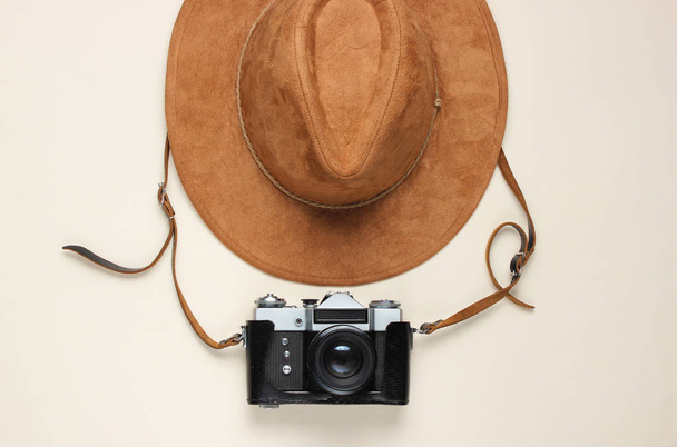 Концепция путешествия. Фелт шляпа и пленка ретро камера на бежевом фоне. Плоский фон путешествия. Вид сверху
 - Фото, изображение