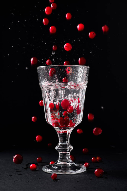 glass of fresh water with juicy cranberries. A lot of berries fl - 写真・画像