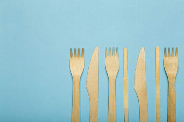 Holzgabeln und Messer für Lebensmittel in einem Pappbecher auf einem farbigen Bac - Foto, Bild