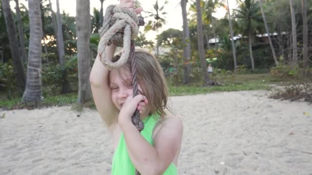 Meisje rijdt op touw op groene palmboom achtergrond - Video