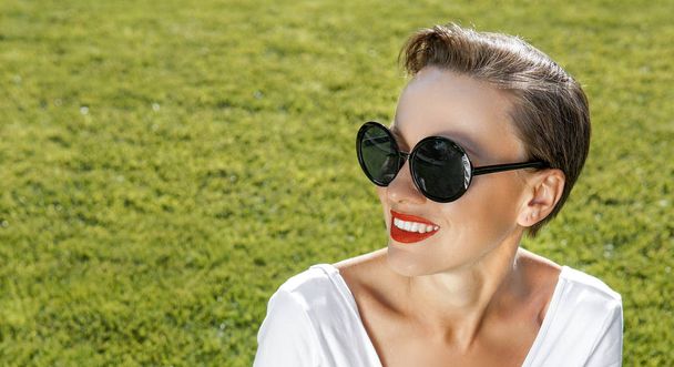 Beautiful woman wearing sunglasses over green natural background - Foto, afbeelding