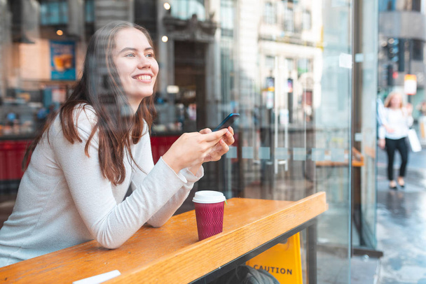 Mulher feliz em um café mensagens de texto com seu smartphone
 - Foto, Imagem