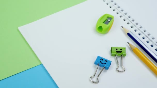 Groene en blauwe glimlach binder clips met gele potloden op notitieblok - Video