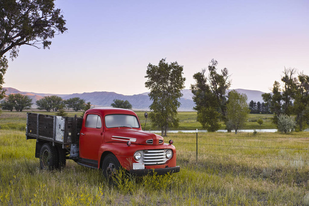 Amerika 'nın batısındaki mor dağların yakınındaki bir çayırda park etmiş eski bir vintage kamyon. - Fotoğraf, Görsel
