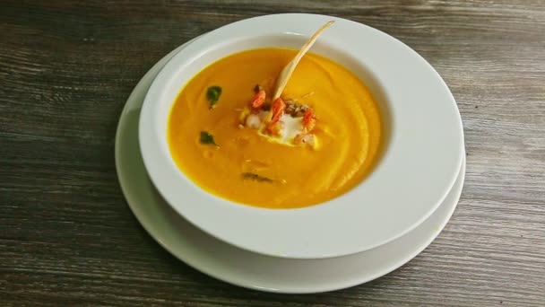 human hand rotates bowl with fish cream soup decorated with prawns tails - Footage, Video