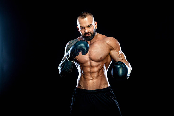 Concepto de fitness y boxeo. Boxeador, hombre luchando o posando con guantes sobre fondo negro. Recreación deportiva individual
. - Foto, imagen