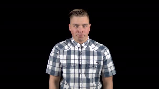 Молодой человек показывает эмоции гнева на своем лице. Злой мужчина в рубашке на черном фоне
 - Кадры, видео