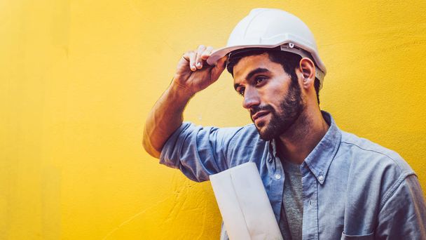 ein junger Ingenieur trägt Blaupause auf gelbem Hintergrund - Foto, Bild
