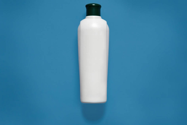 Cosmetic package, mockup, white empty plastic bottle with black cap, containers, clean plastic container, copy space for promotional text or advertisment, isolated over blue studio background. - Foto, Bild