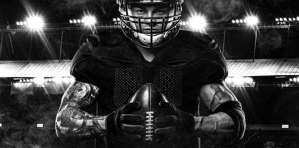 Sport concept. American football sportsman player on dark background with lights. Sport concept. - Fotó, kép