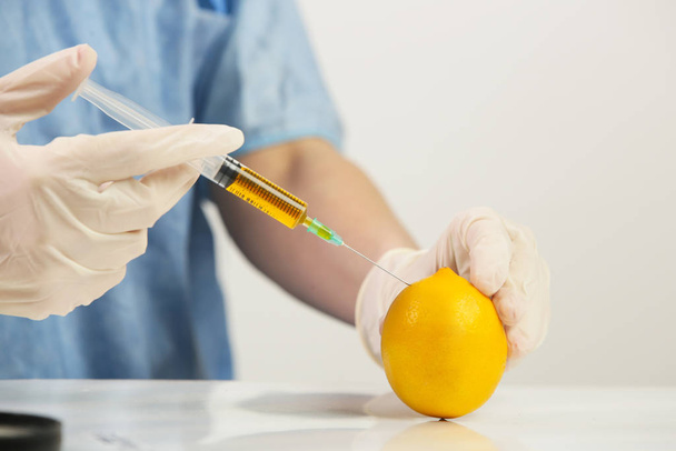 Closeup of needle injected into lemon, Genetically engineered food concept - Photo, Image