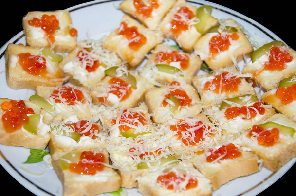 small canapes with red caviar. Close-up. Bruschettas on a plate. Black background. - Photo, Image