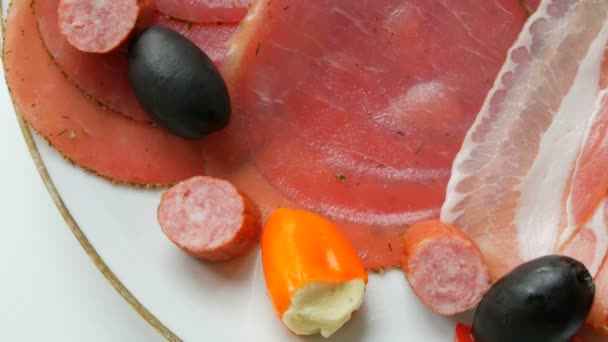 Viande et tranches de saucisse dans une assiette à côté des olives noires, paprika au fromage et saucisses de chasse. Salami et jambon tranché. Viande séchée arrangée au restaurant. C'est appétissant. Assiette de viande séchée
 - Séquence, vidéo