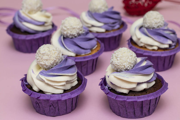 Házi készítésű sütemények lila krémmel rózsaszín alapon, fogalom Valentin napra vagy születésnapra, vízszintes eligazítás - Fotó, kép