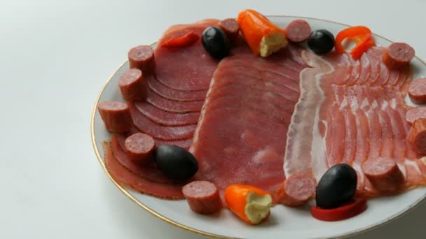 Vlees- en worstschijfjes op bord naast zwarte olijven, paprika met kaas en jachtworsten. Salami en gesneden ham. Geregeld gedroogd vlees in restaurant. Smakelijk. Gezouten vleesplaat - Video