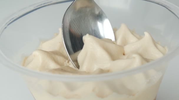Dessert aus Schlagsahne und Schokolade in Plastikbecher. weibliche Hand mit Teelöffel entfernt die Oberseite der Creme - Filmmaterial, Video