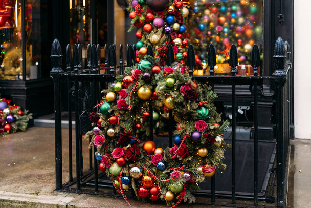 Beautiful Fresh handmade Christmas wreath decorated with colored balls, flowers, Christmas decorations and fir cones in a shop window. Christmas holiday concept. - Photo, Image