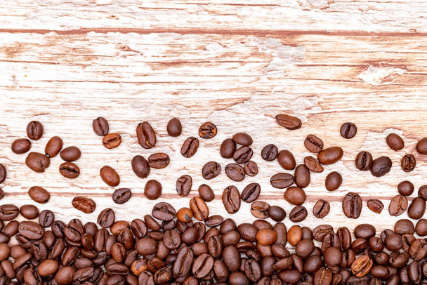 granos de café tostados esparcidos sobre un fondo con una textura de madera. café mania.close up
. - Foto, imagen