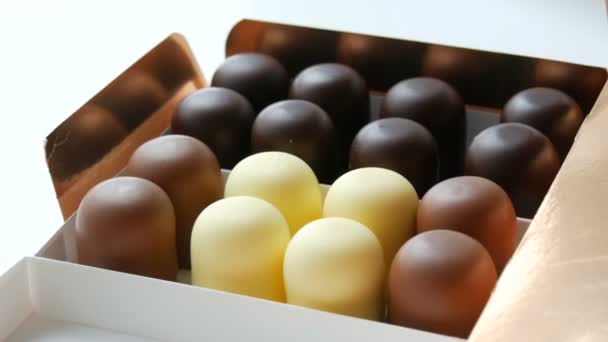 白、黒、ミルクチョコレートの釉薬でお菓子の形で風通しの良いスフレデザートをビズ。白いテーブルの上にチョコレートの箱 - 映像、動画