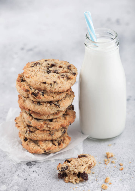 Homemade organic oatmeal cookies with raisins and apricots and bottle of milk on light background. - Photo, Image