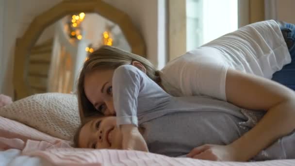 Moeder en dochter rotzooien in bed, lachen en kietelen elkaar - Video