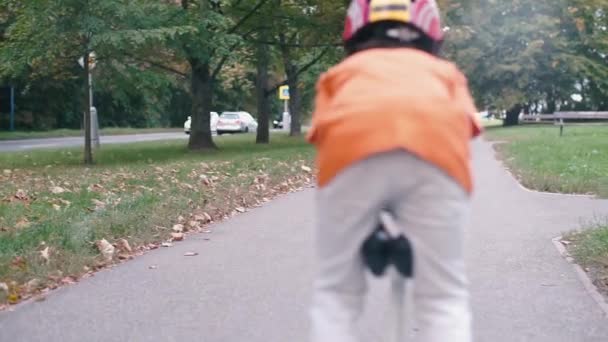 a schoolboy in an orange shirt in a helmet leaves on a GyroScooter - Materiał filmowy, wideo