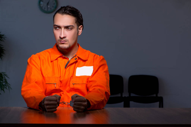 Junger Häftling sitzt in dunklem Raum - Foto, Bild