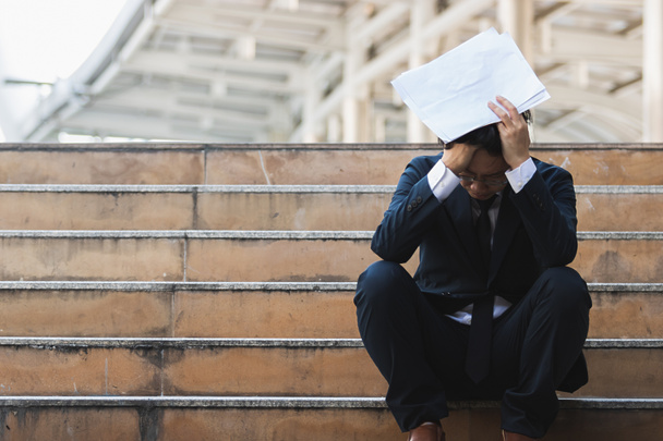 Työttömät stressaantunut nuori aasialainen liikemies istuu portaikossa ulkona. Epäonnistumisen ja lomautuksen käsite
. - Valokuva, kuva