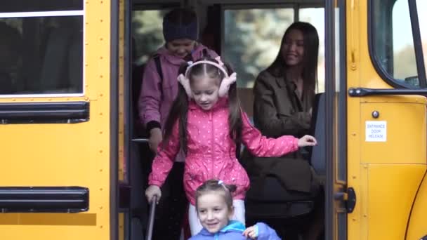 słodkie małe uczennice wysiadając z autobusu szkolnego - Materiał filmowy, wideo