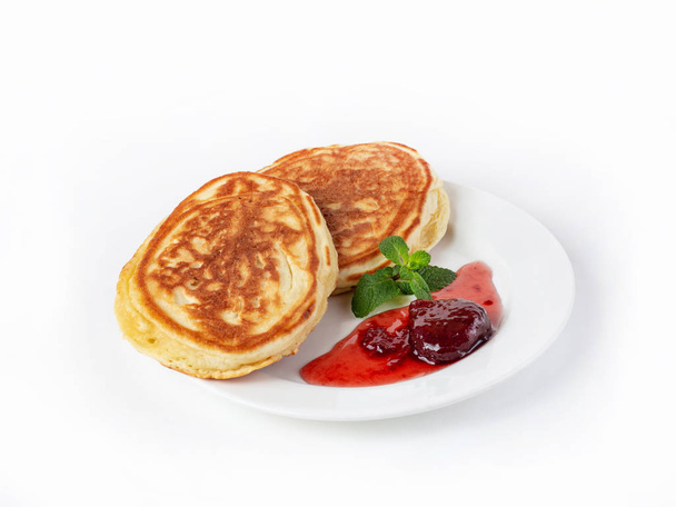 Two large pancakes on a plate with strawberry jam and mint leaves side view - Фото, зображення