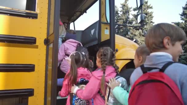 Fröhliche kleine Schulkinder steigen in Schulbus - Filmmaterial, Video