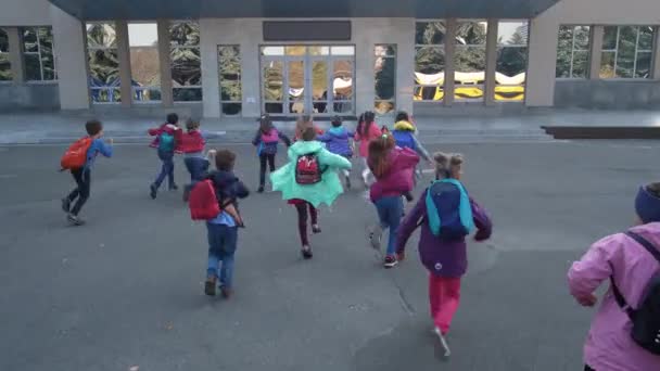 Fröhliche Grundschulkinder rennen zur Schule - Filmmaterial, Video