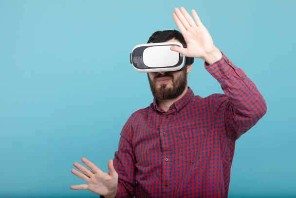 Young man using VR glasses headset trying to touch objects in virtual reality. Isolated white background. - Fotografie, Obrázek