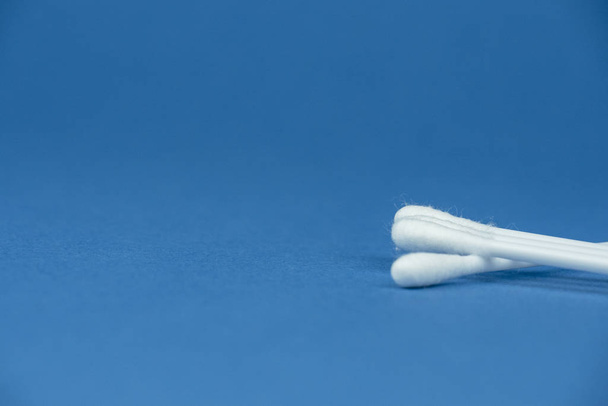 White sticks for cleaning ears lie on the right on a blue background. - Foto, imagen