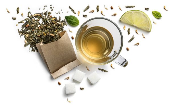 Groene thee met natuurlijke aromatische toevoegingen en een kopje. Bovenaanzicht op witte achtergrond - Foto, afbeelding