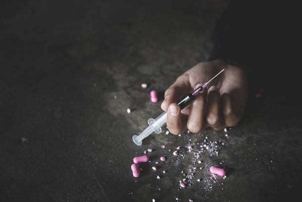 Die menschliche Hand eines Drogenabhängigen und eine Spritze mit Betäubungsmitteln  - Foto, Bild
