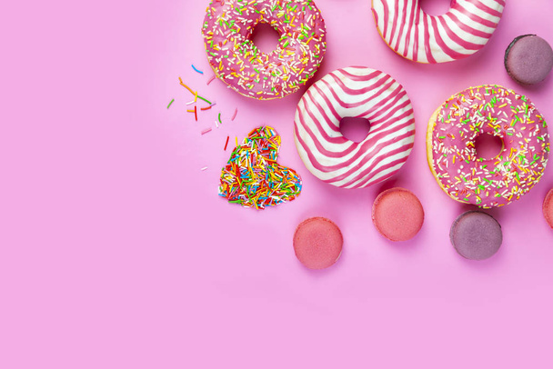 Donuts and macaroons on a pink background. - Photo, image