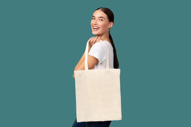 Kobieta z białym Tote torba na zakupy pozowanie, Turkusowe tło - Zdjęcie, obraz