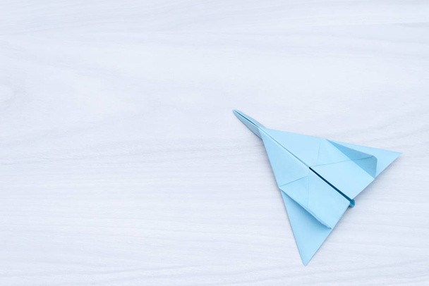 Flat lay of blue paper plane on white wooden background. Copy space. Travel concept. - Zdjęcie, obraz