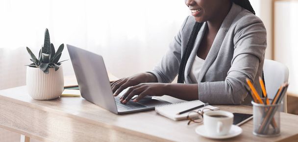 Onherkenbaar Afrikaans Amerikaans secretaresse werkt op laptop in kantoor - Foto, afbeelding
